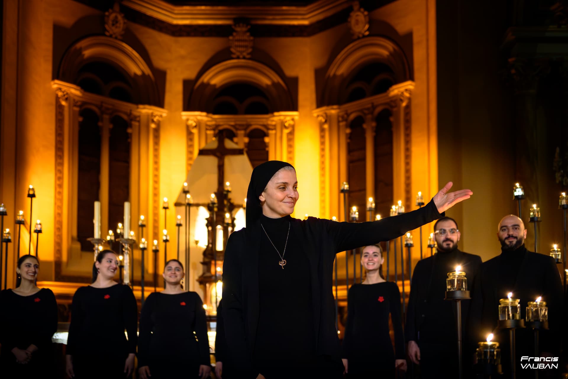Une soliste salue les chanteurs de la chorale devant les bougies